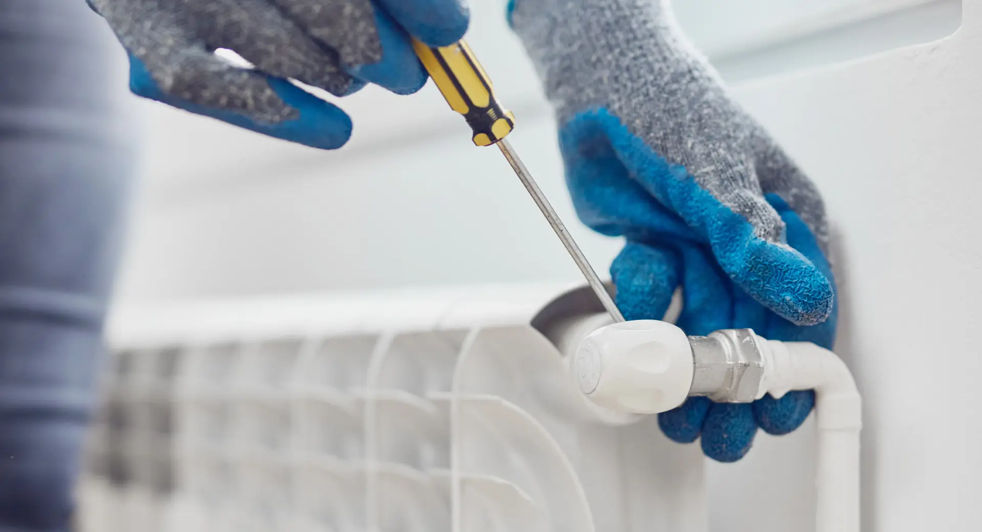 Worker using a screwdriver on a radiator