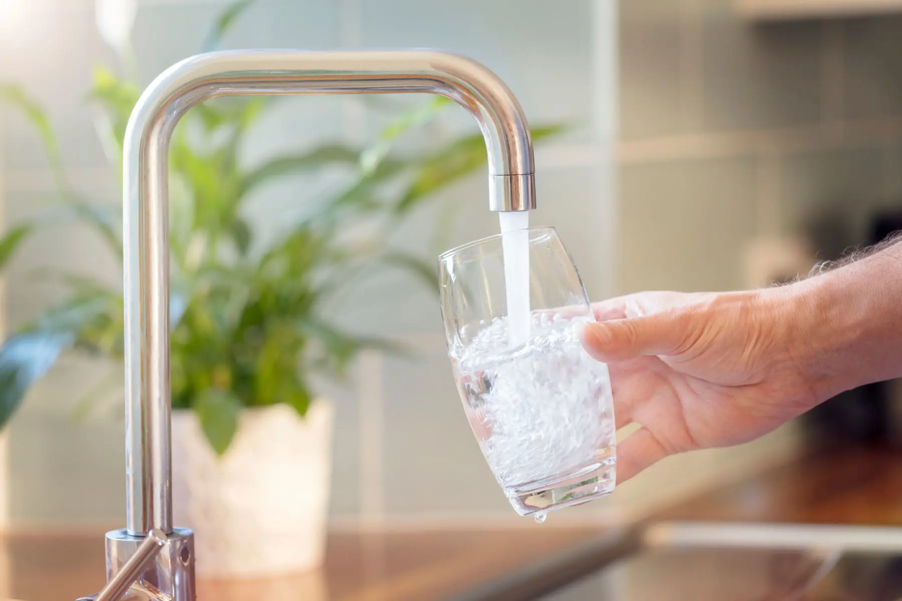 Man's hand filling up a glass of water 