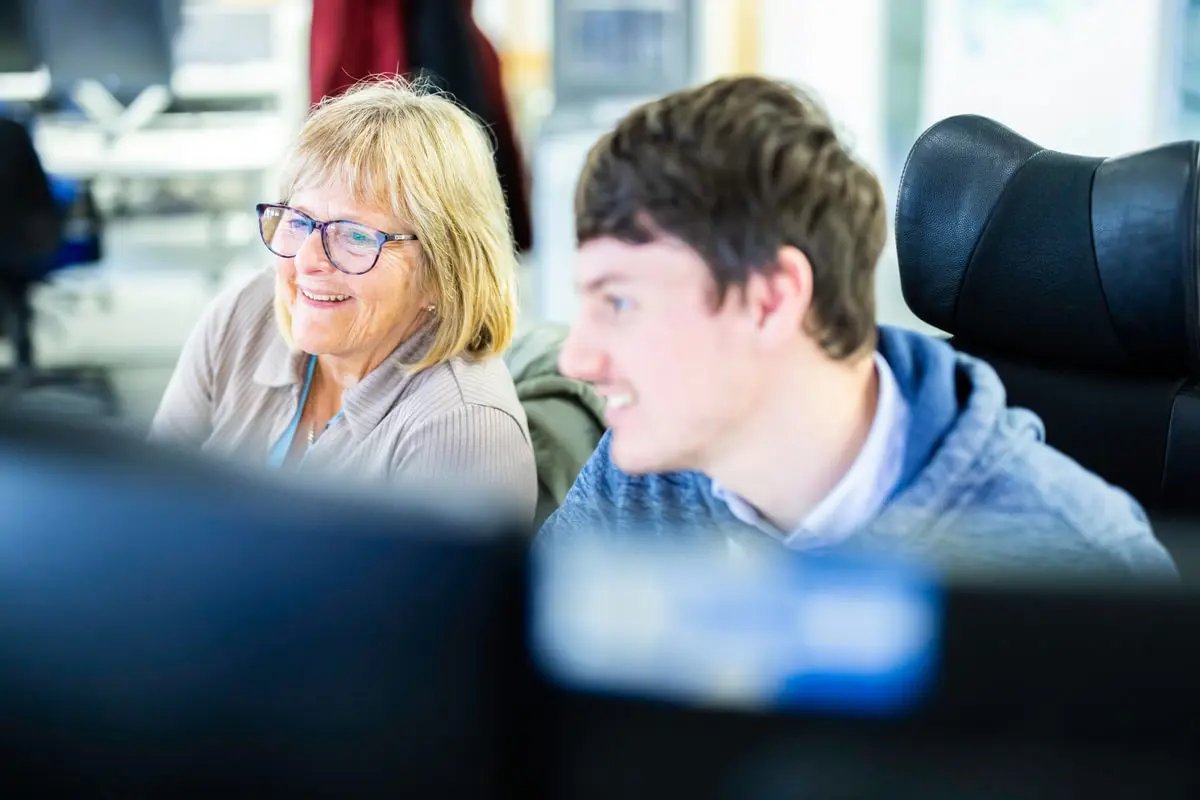 woman showing a young apprentice how to do something on a computer 