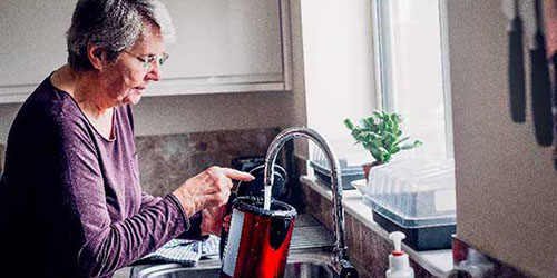 Lady filling up kettle from the tap