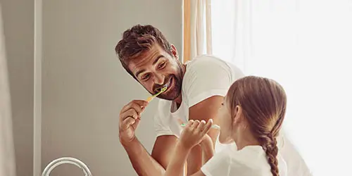 Man brushing teeth with his daughter