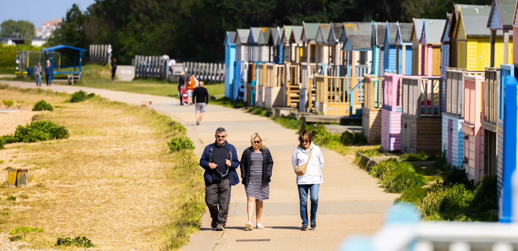 A close up shot of beach huts lining a promenade with people walking